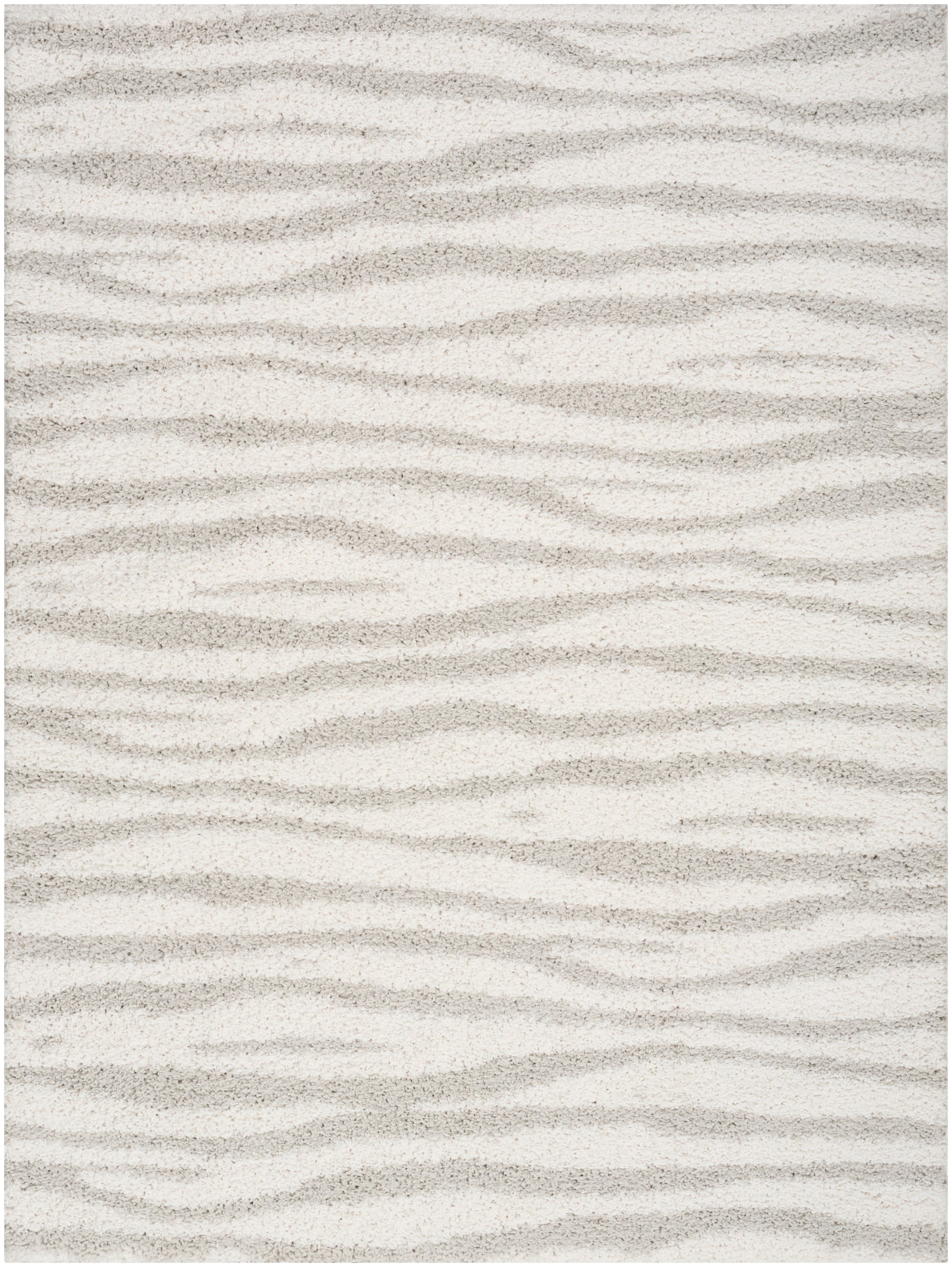Beige plush rug with cream and taupe wavy stripes resembling sand dunes and a soft texture.