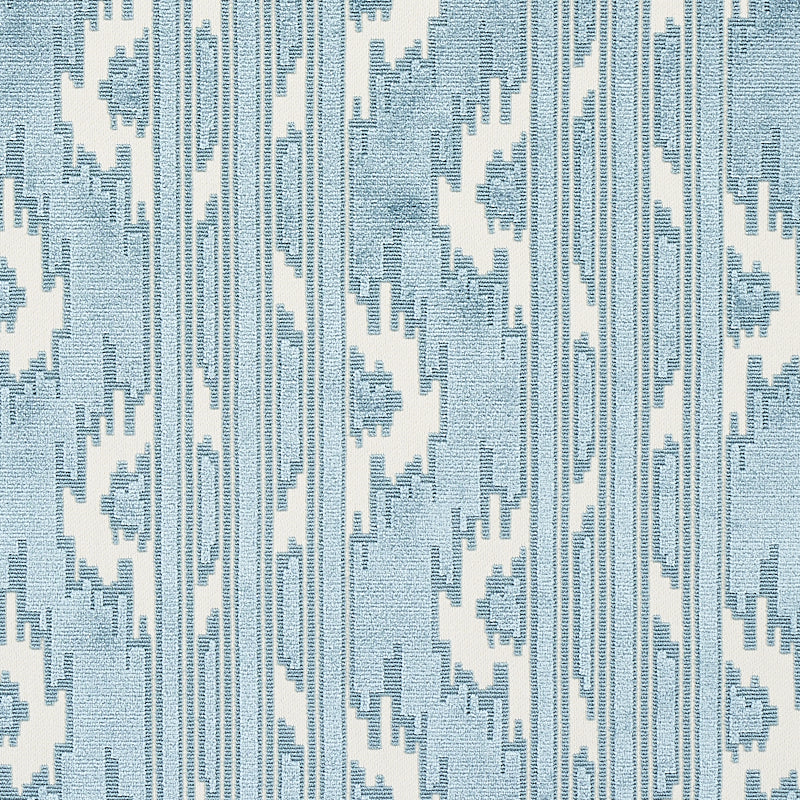 Blue and white ikat-inspired fabric with vertical zigzag stripes and geometric motifs.