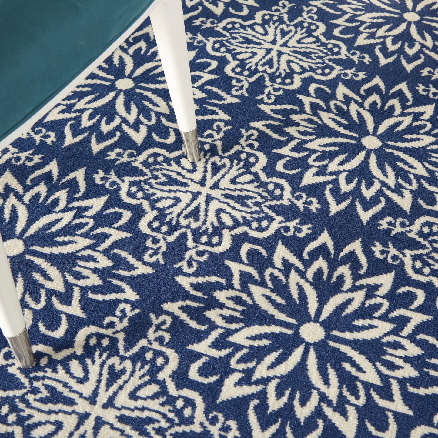 Navy rug with white snowflake floral motifs; white table legs visible in corner.