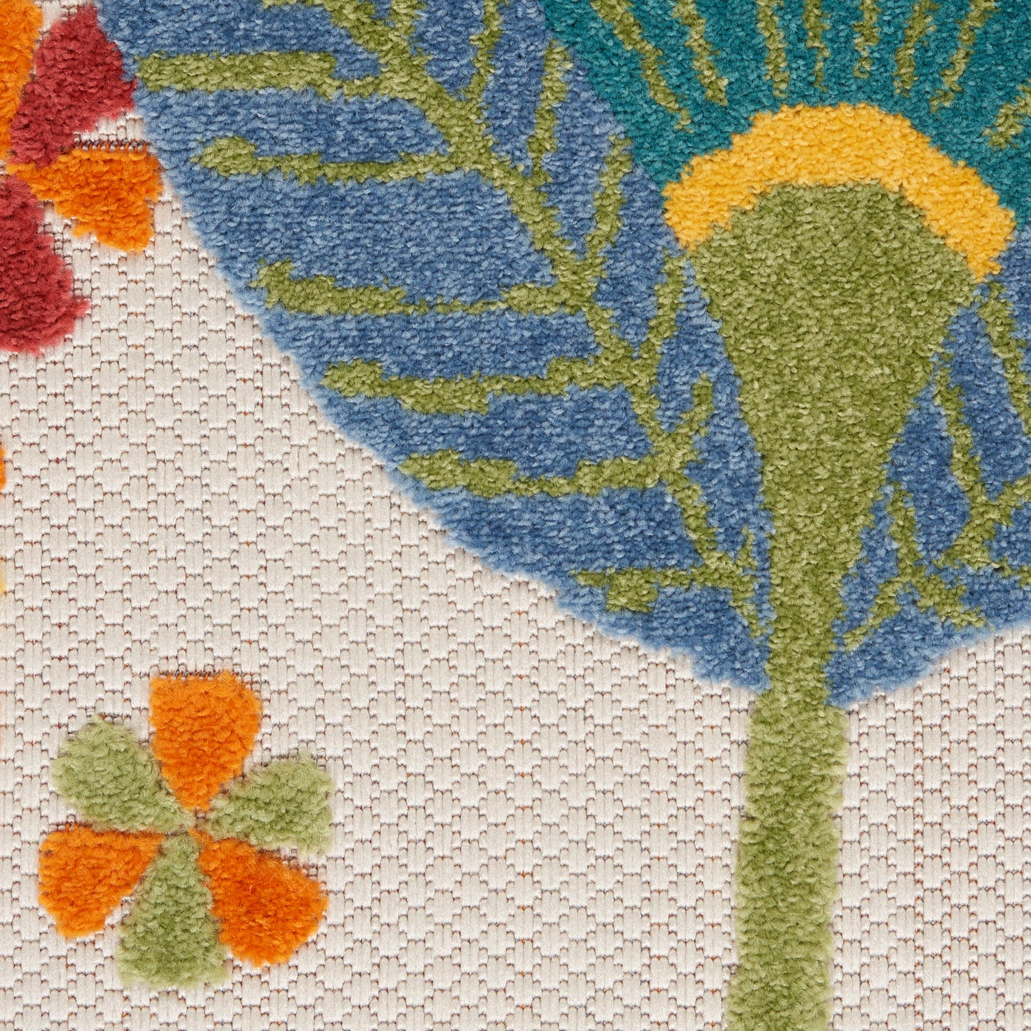 Close-up of a tufted rug featuring blue floral motif with green stems on a beige background and orange accents.