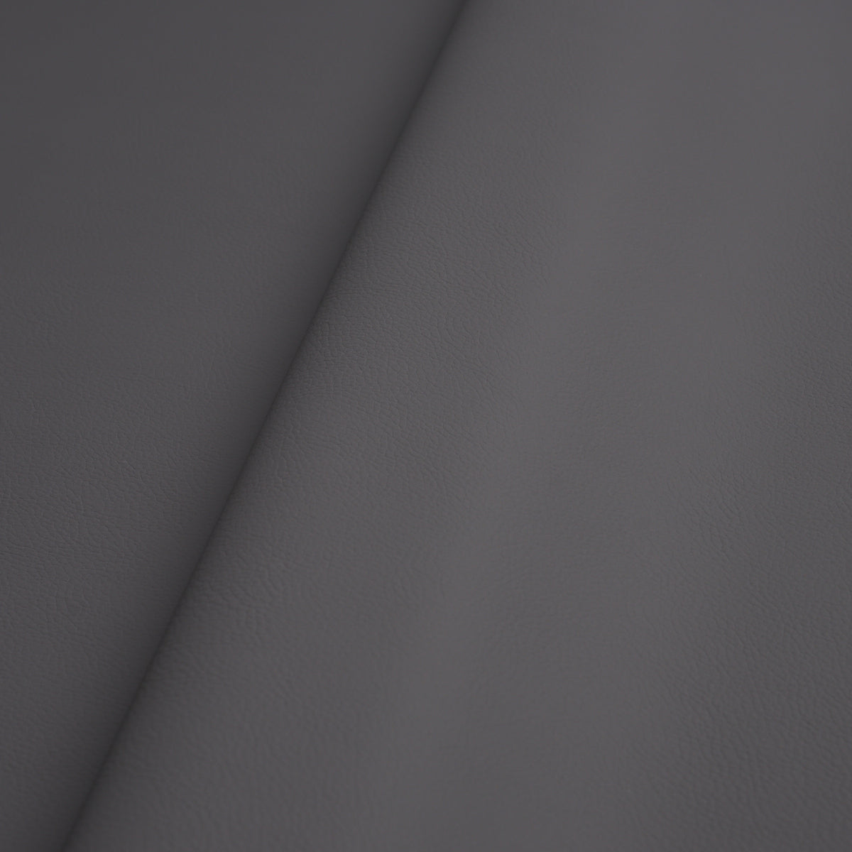 Charcoal grey pebbled leather with diagonal seam, premium upholstery texture.