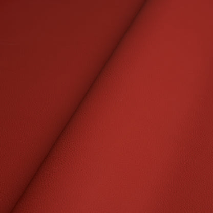 Close-up of red leather-textured material with visible grain and a diagonal fold.