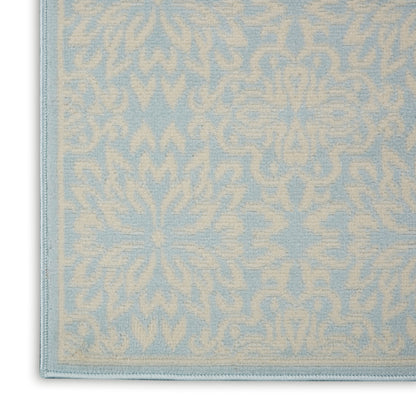 Light blue rug with cream damask floral pattern and stitched border, close-up corner view.