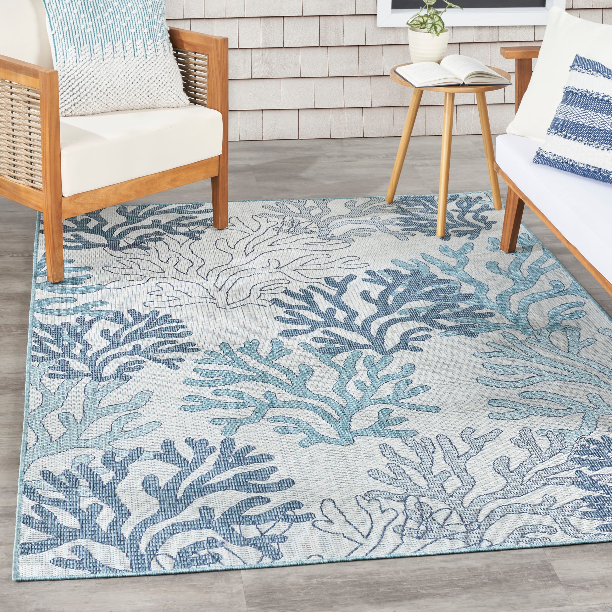 Rectangular outdoor rug with blue coral pattern on a light gray backdrop; woven coastal textile for patio seating.