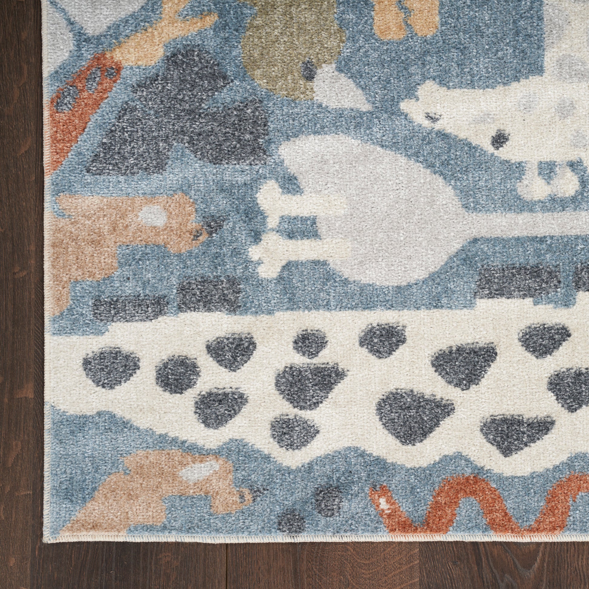 Abstract blue and cream area rug with tan and orange accents on wood floor.