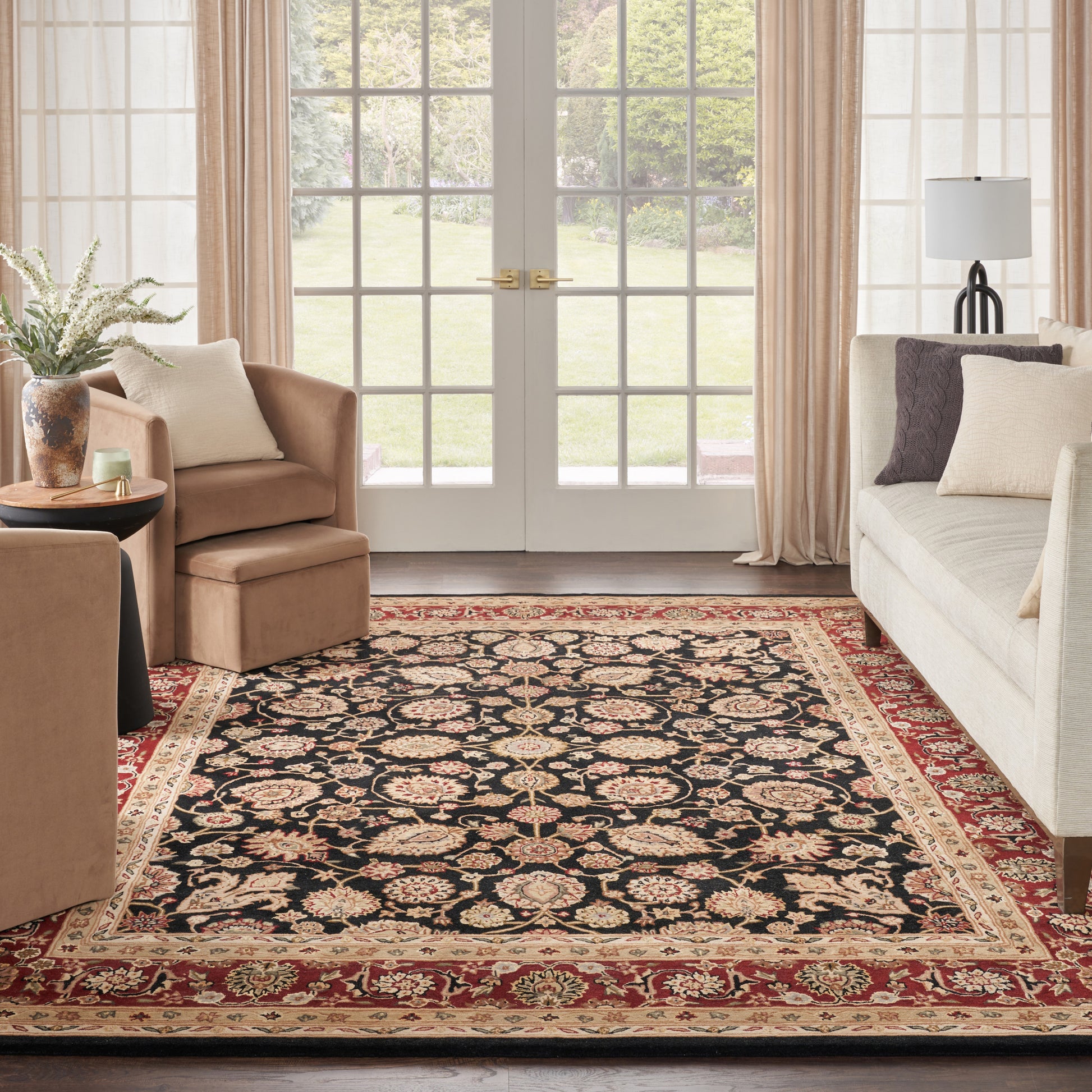 Traditional Persian-style rectangular area rug with black field, floral motif, red-and-gold border, in a beige living room.