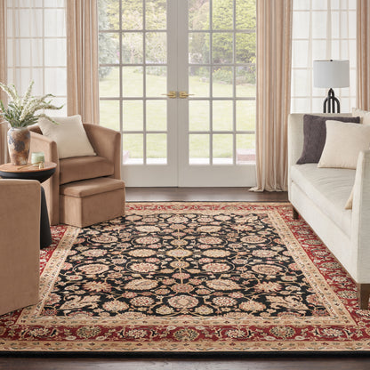 Traditional Persian-style rectangular area rug with black field, floral motif, red-and-gold border, in a beige living room.