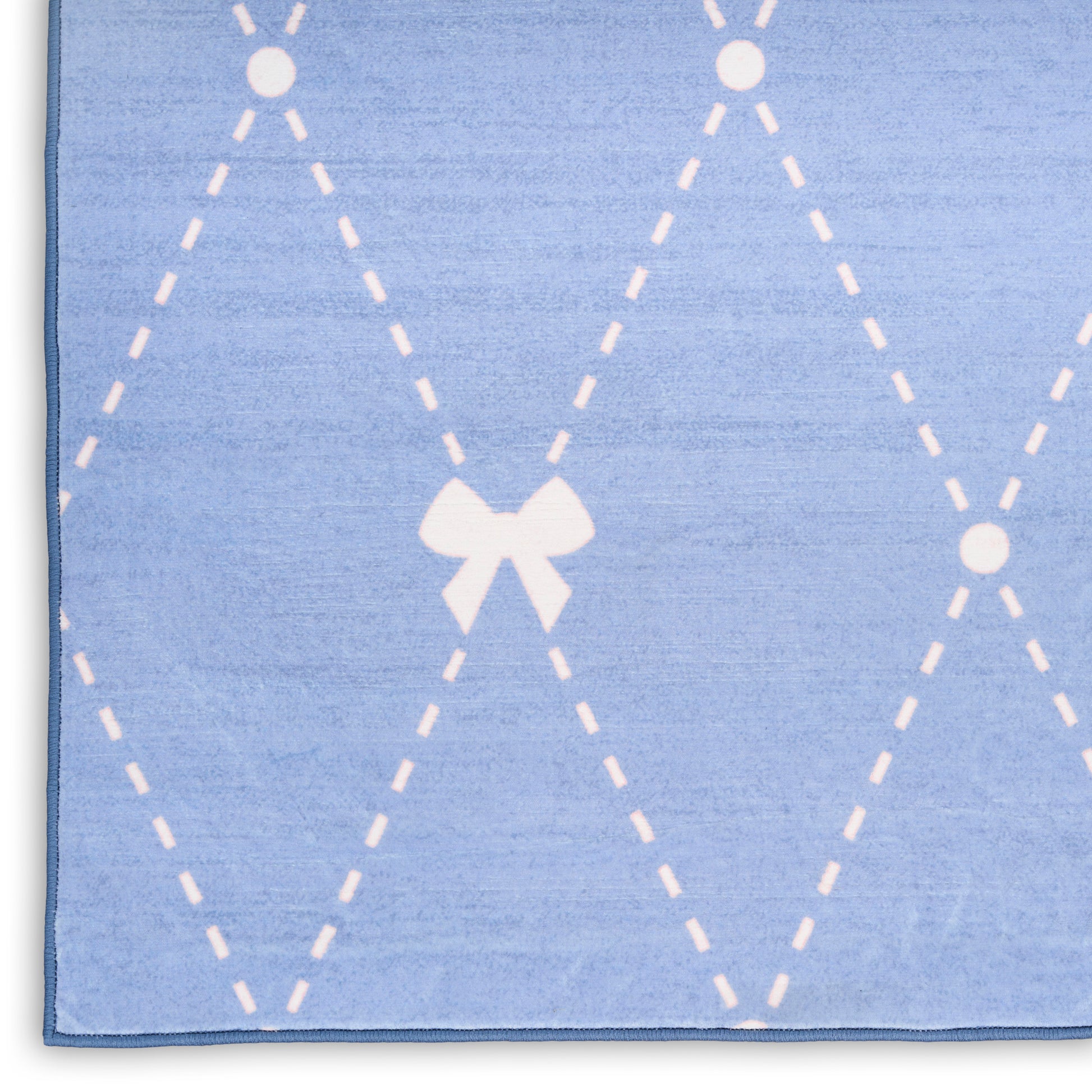 Soft light-blue rug with white dashed argyle diamonds and a centered bow motif.