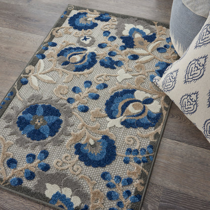 Floral blue, beige & gray area rug with ornate pattern on wood floor beside a light sofa.