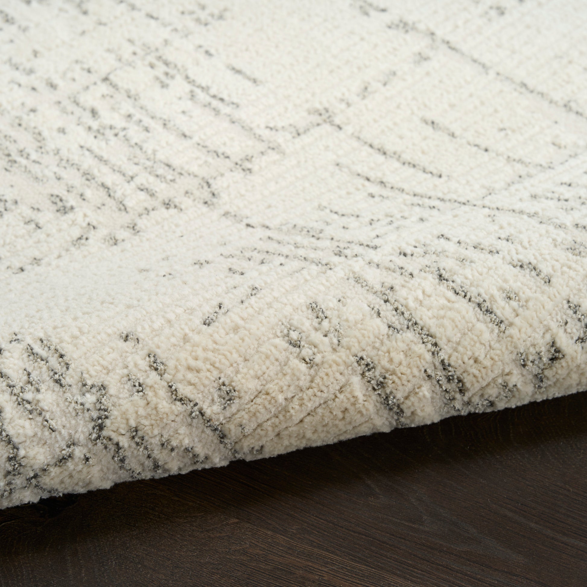 Cream textured rug with gray abstract geometric lines, plush pile on dark wood floor.