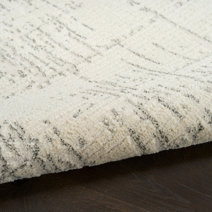 Cream textured rug with gray abstract geometric lines, plush pile on dark wood floor.