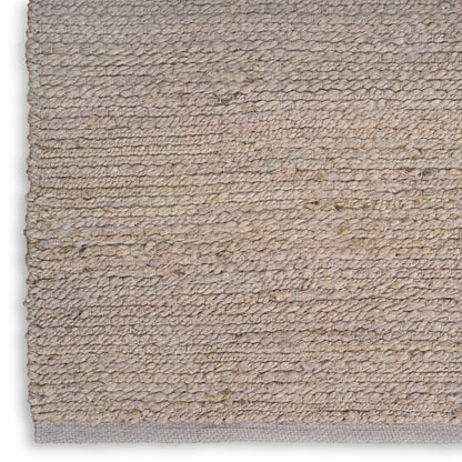 Beige natural-fiber loop-pile rug with subtle texture and grey backing along edge.