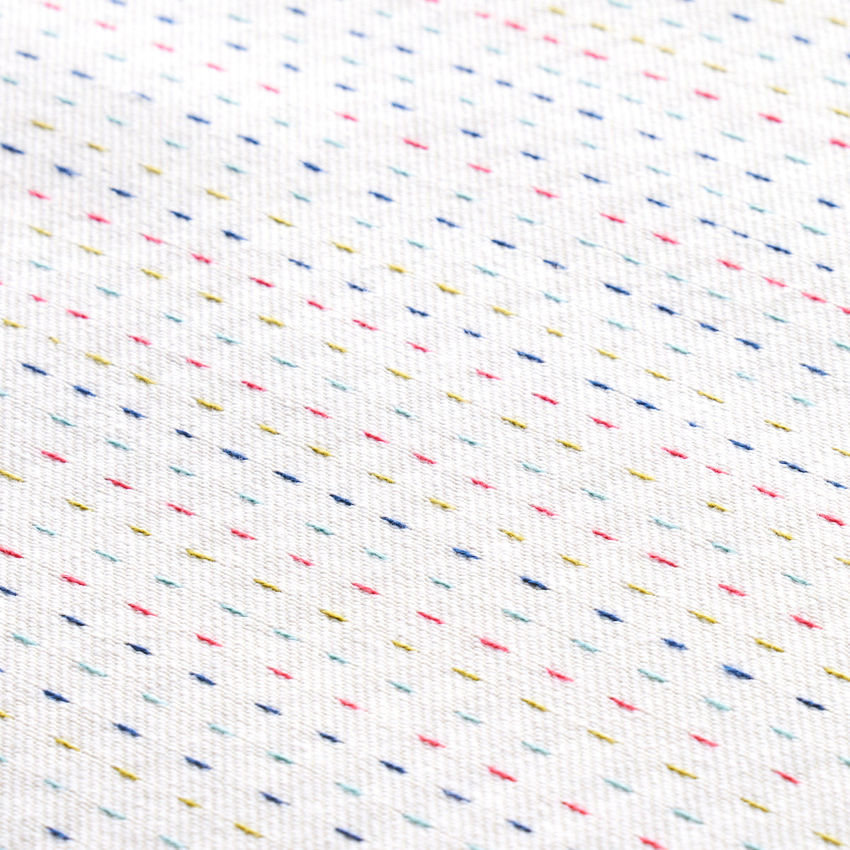 White fabric with tiny multicolored diagonal dashes in blue, pink, yellow and green.