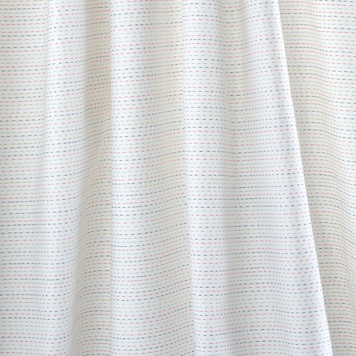 White fabric curtain with fine blue and red dashed stripes, soft folds.