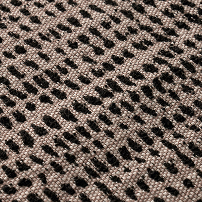 Beige woven fabric with irregular black dot pattern and textured surface.