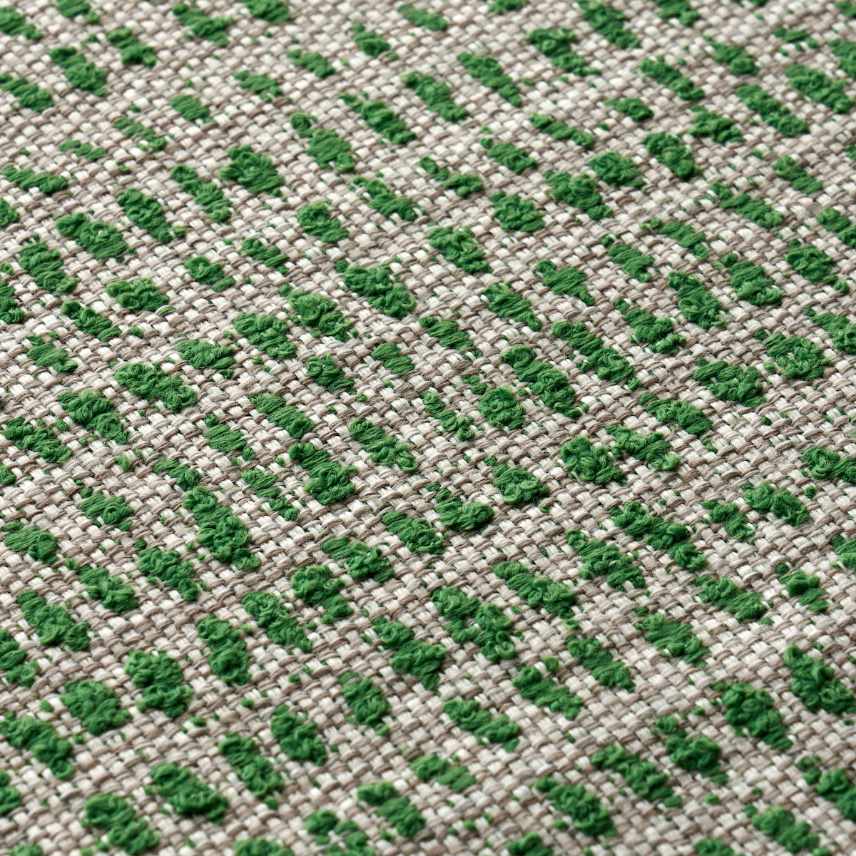 Beige woven fabric with emerald green dotted geometric pattern; textured upholstery or rug material.