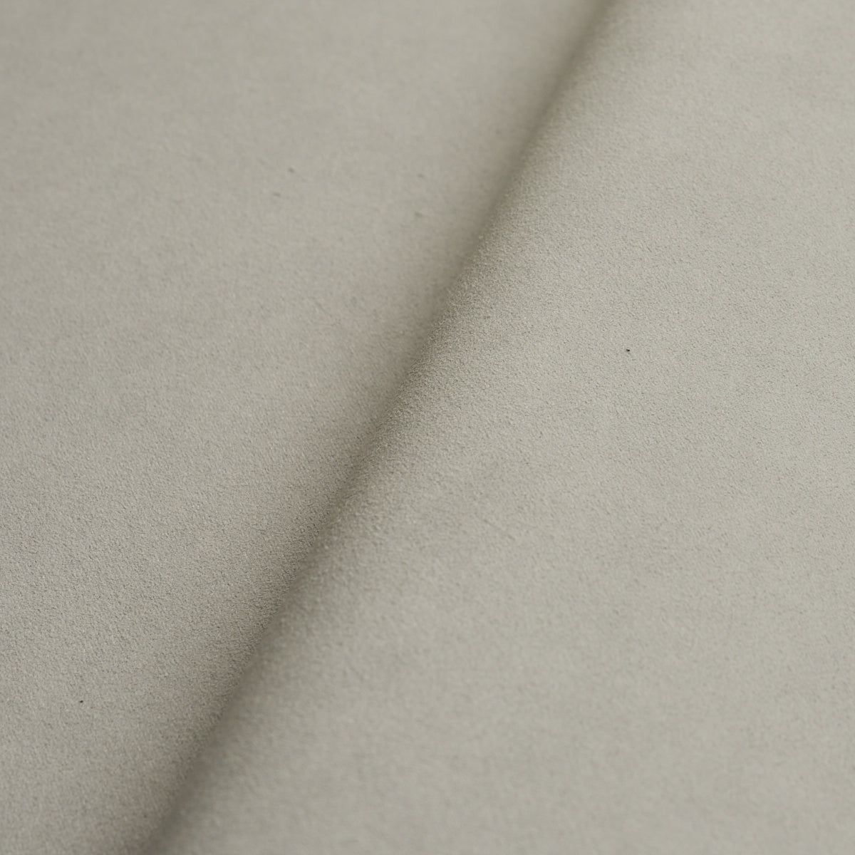 Beige suede-like fabric close-up with a diagonal fold; soft texture for upholstery or apparel.