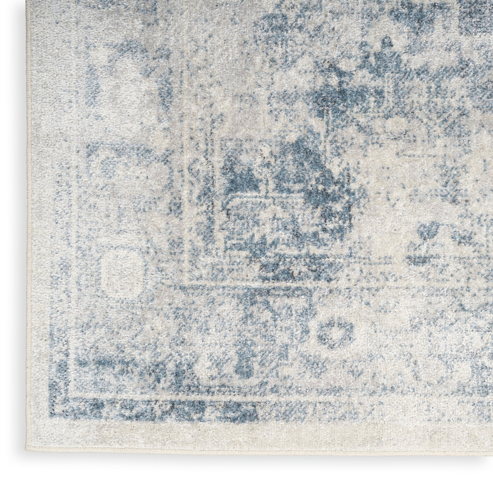 Rectangular ivory rug with a faded blue oriental/Persian pattern and distressed vintage look.