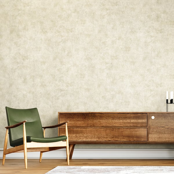 Beige wallpaper with a subtle corded texture serving as backdrop to a mid-century green upholstered chair with a wooden frame and a long walnut sideboard.