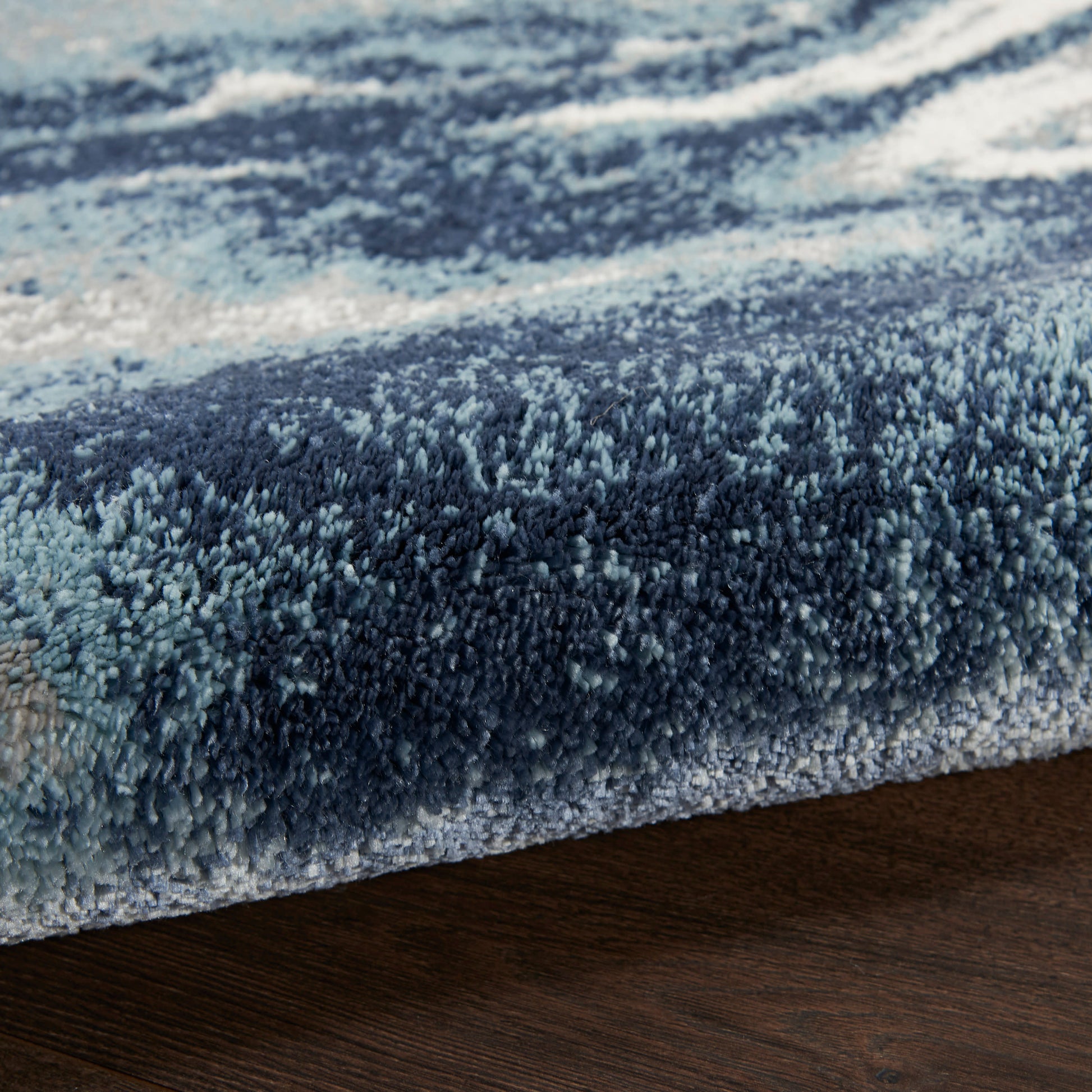 Blue gradient shag rug with dense microfiber pile, edge visible on a wooden floor.
