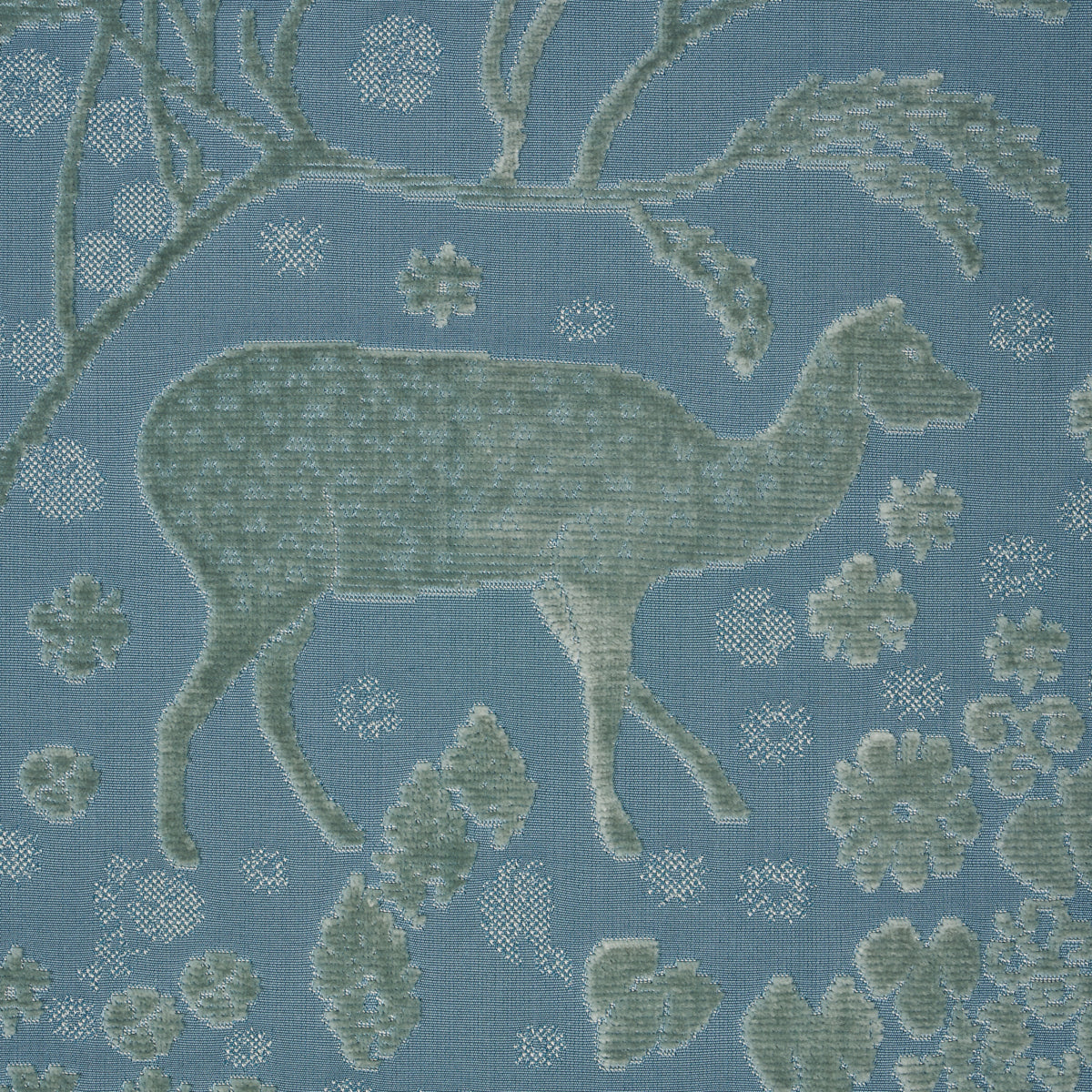Blue tapestry-style upholstery fabric with sage deer silhouette, branches & floral motifs in a woven jacquard pattern.