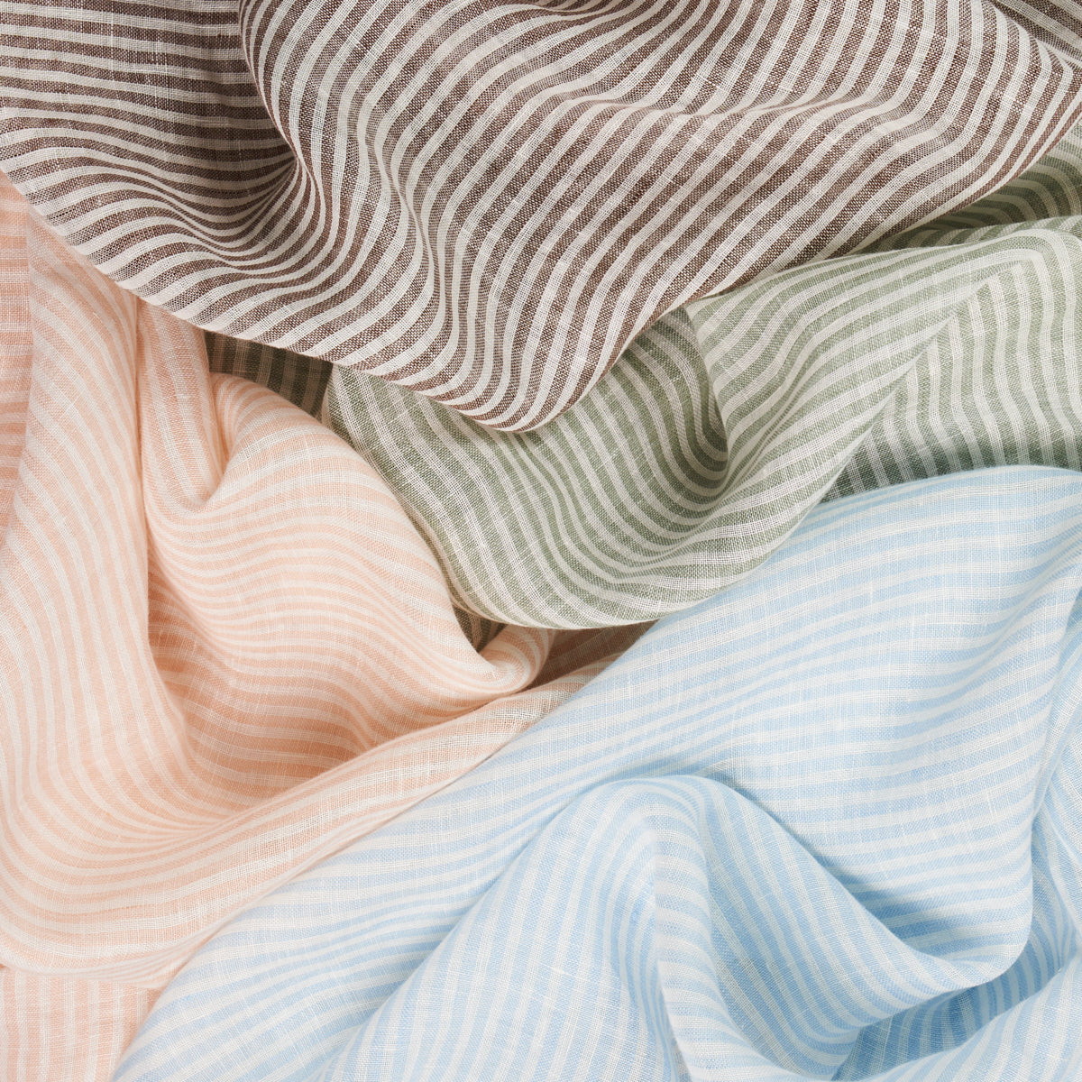 Soft pastel striped fabrics in peach, taupe, sage green, and light blue, draped in gentle folds.