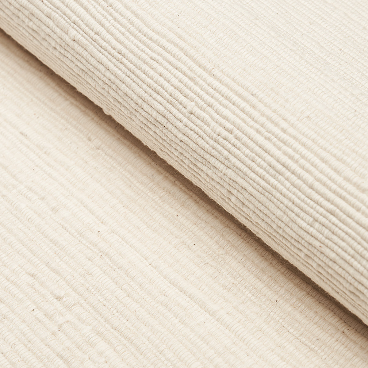 Beige corduroy fabric rolled, featuring distinct vertical ridges and soft plush texture.