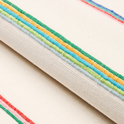 Beige canvas with multicolor embroidery trim along edge in green, blue, yellow & orange; casual decorative textile detail.