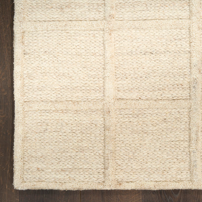 Cream tufted rug with square-grid panels on dark wooden floor.