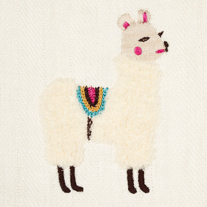 Cream llama embroidery on canvas with pink ears and cheeks, brown hooves, multicolor saddle blanket; rustic stitch art.