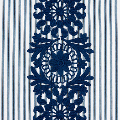 Deep blue embroidered lace panel featuring circular floral medallion and leaf motifs on striped blue-and-white fabric.