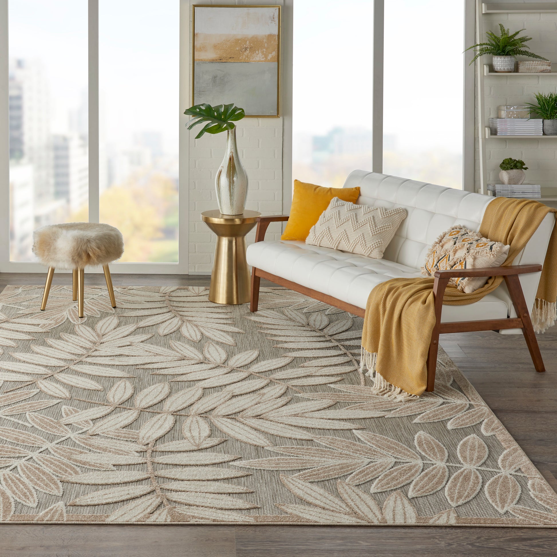Modern cozy living room: beige-gray leaf-pattern woven rug, white mid-century sofa, mustard throw, warm wood accents and plants.