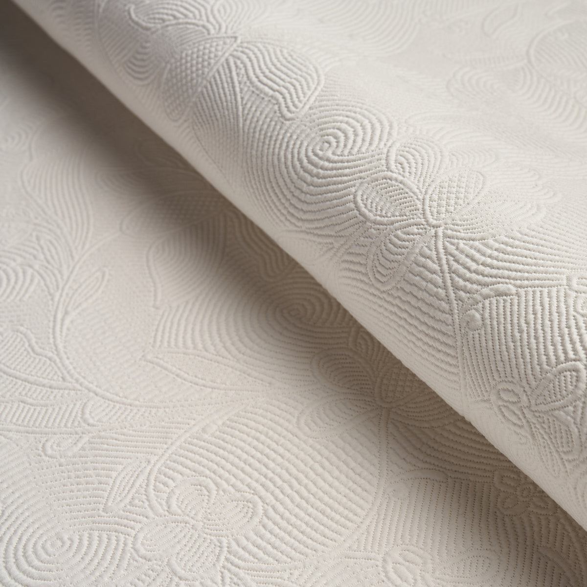 Cream damask jacquard fabric with embossed floral scroll pattern and textured finish.