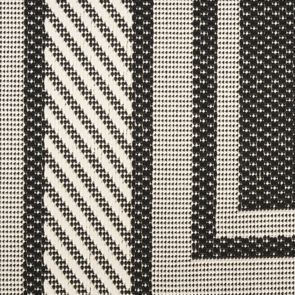 Monochrome woven fabric with bold black vertical stripes and diagonal chevron patterns on ivory background.