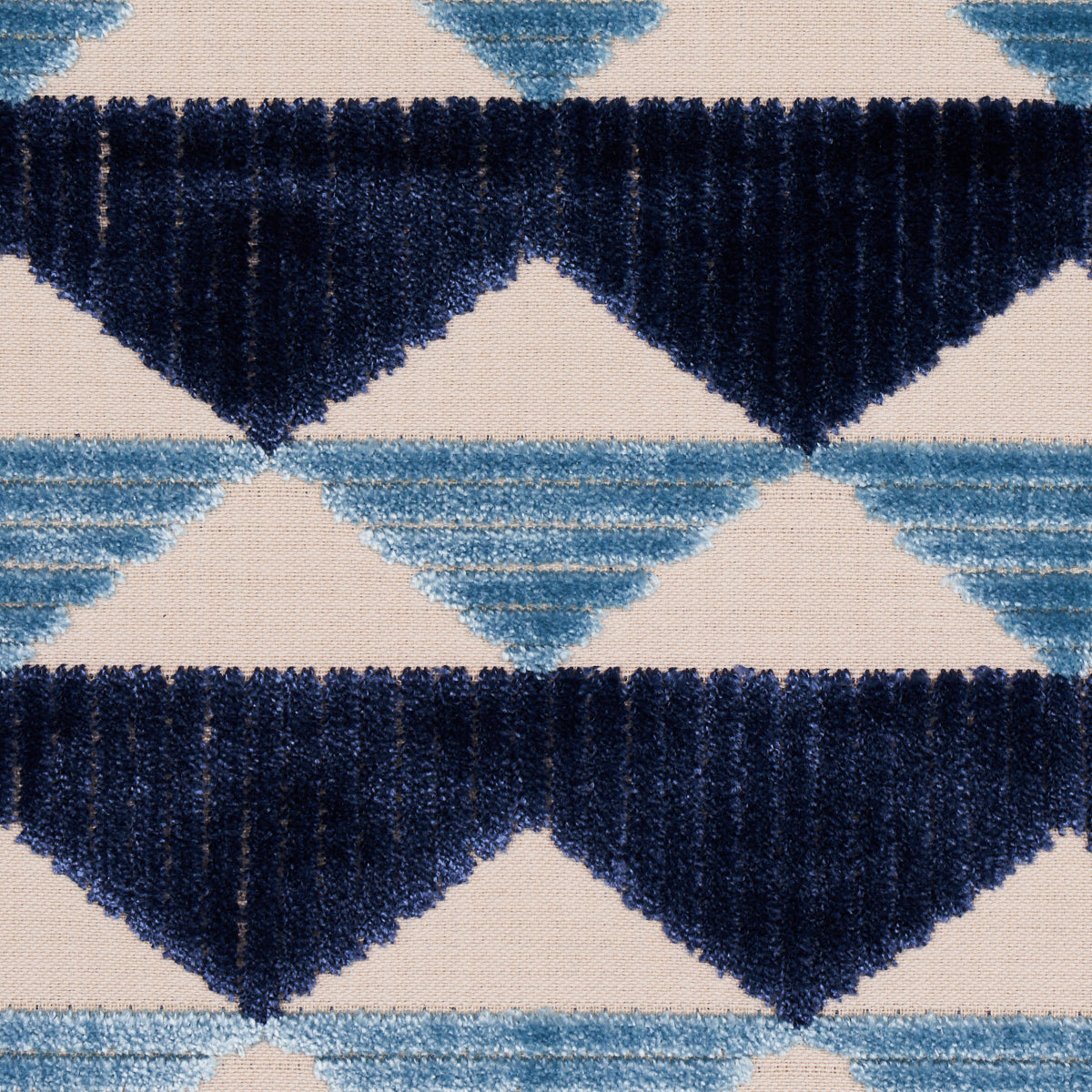 Plush geometric rug with navy and light blue diamond triangles on beige background.