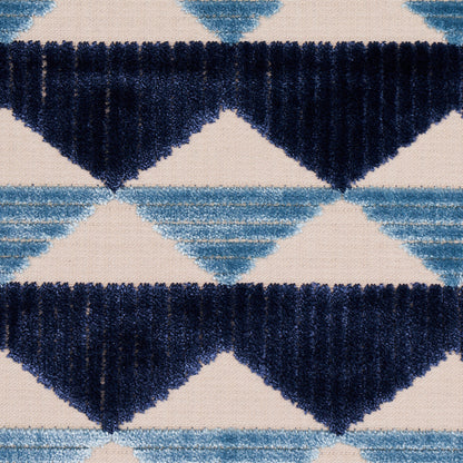 Plush geometric rug with navy and light blue diamond triangles on beige background.