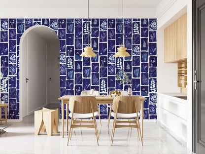 Dining area featuring navy botanical-pattern wall mural, with light wood table and chairs, pendant lights, arch doorway and white kitchen.