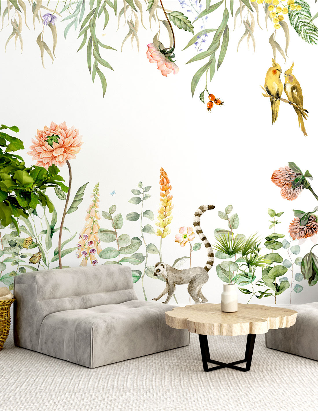 Green tropical wall mural with botanical elements—vines, leaves, flowers and birds—in watercolor style; living room scene with a gray sofa.