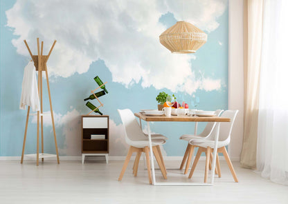 Dining area featuring a green nature wall mural; light wood table, white chairs, woven rattan pendant lamp; coat rack and plant stand.