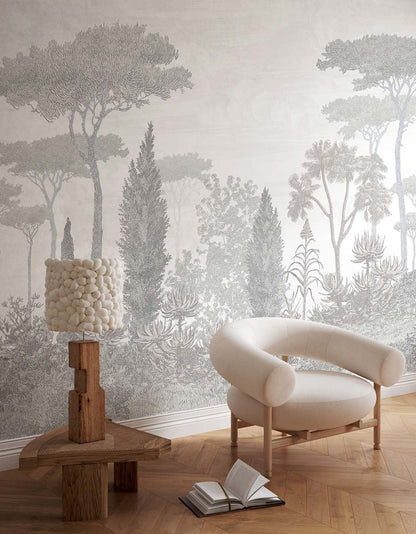 Neutral living room with forest wallpaper, rounded beige boucle chair, wooden pedestal lamp with pom-pom shade.