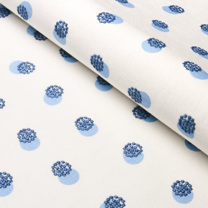 White fabric with light blue circles, each with a darker blue cluster, forming a dotted floral-like pattern