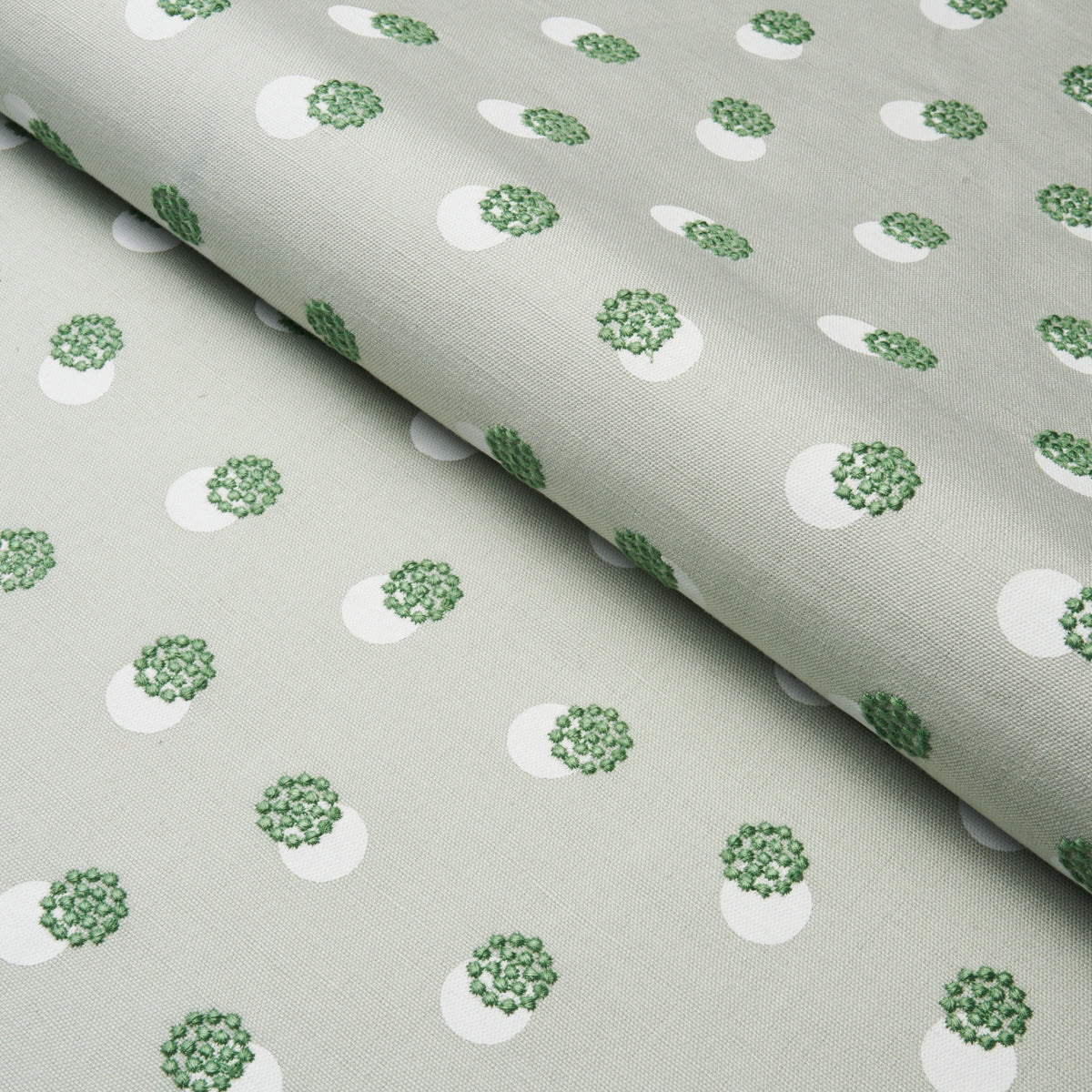 Light grey woven fabric with white circular motifs containing green floral clusters; subtle repeating pattern.