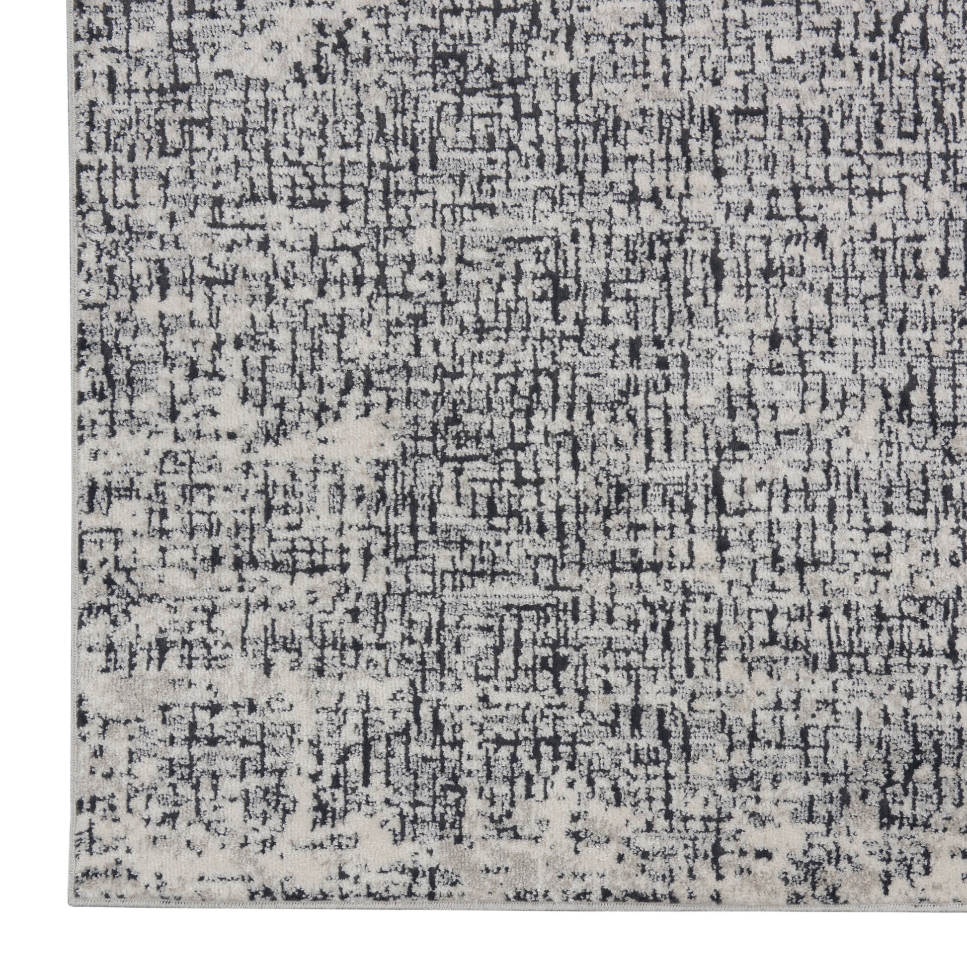 Rectangular distressed rug in charcoal, grey and ivory with a modern abstract pattern.