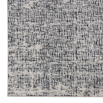 Rectangular distressed rug in charcoal, grey and ivory with a modern abstract pattern.