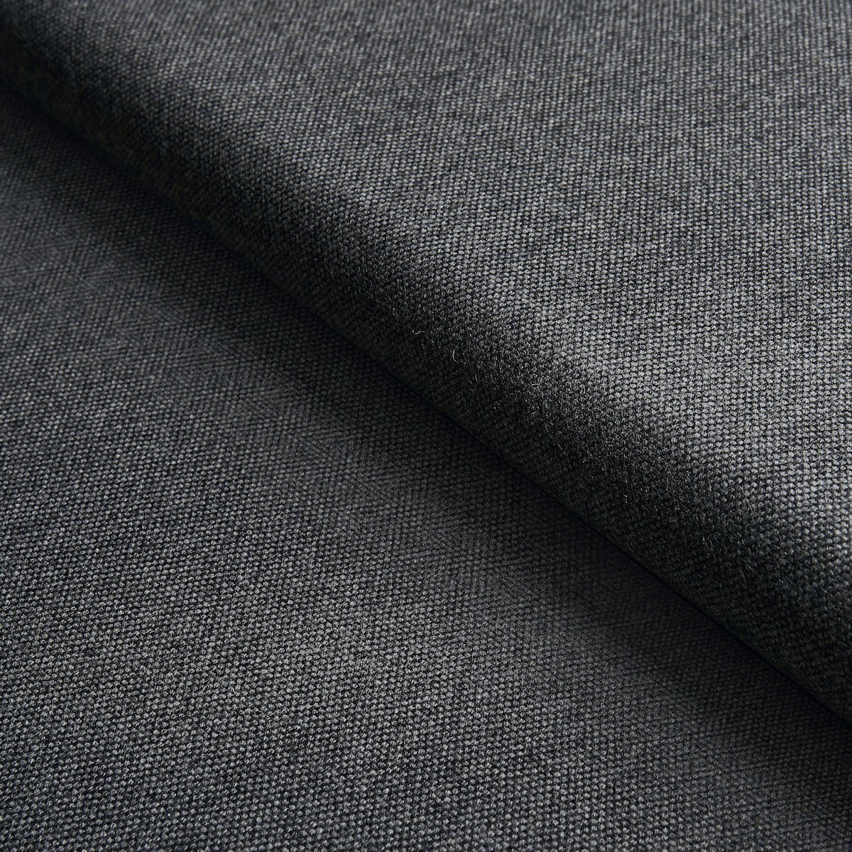 Close-up of charcoal gray woven fabric with a folded edge, fine twill texture suitable for suits.