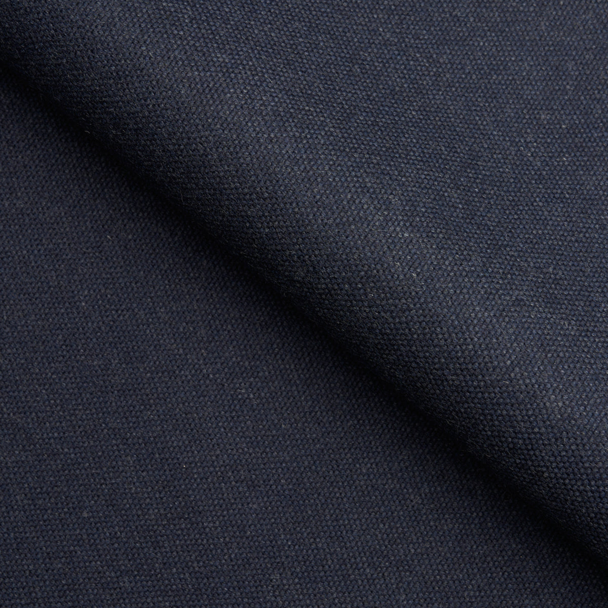 Close-up of dark navy woven fabric with a diagonal fold and tight textured weave, ideal for garments.