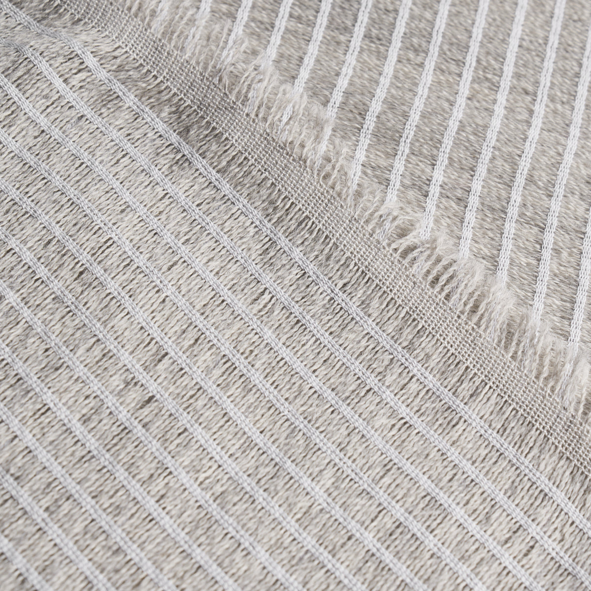 Beige striped woven rug with white fringe edge; soft cotton throw for living room decor.