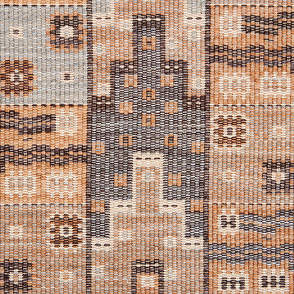 Geometric woven rug in tan, beige and gray-blue with a castle-like central motif and dotted accents.