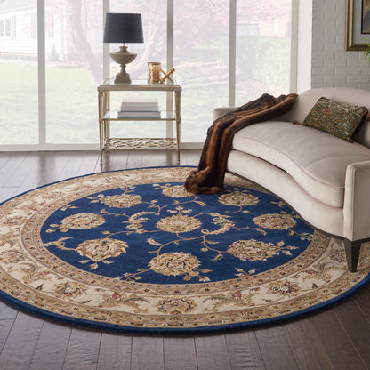 Round blue and beige floral rug under a cream sofa with a fur throw and gold side table.