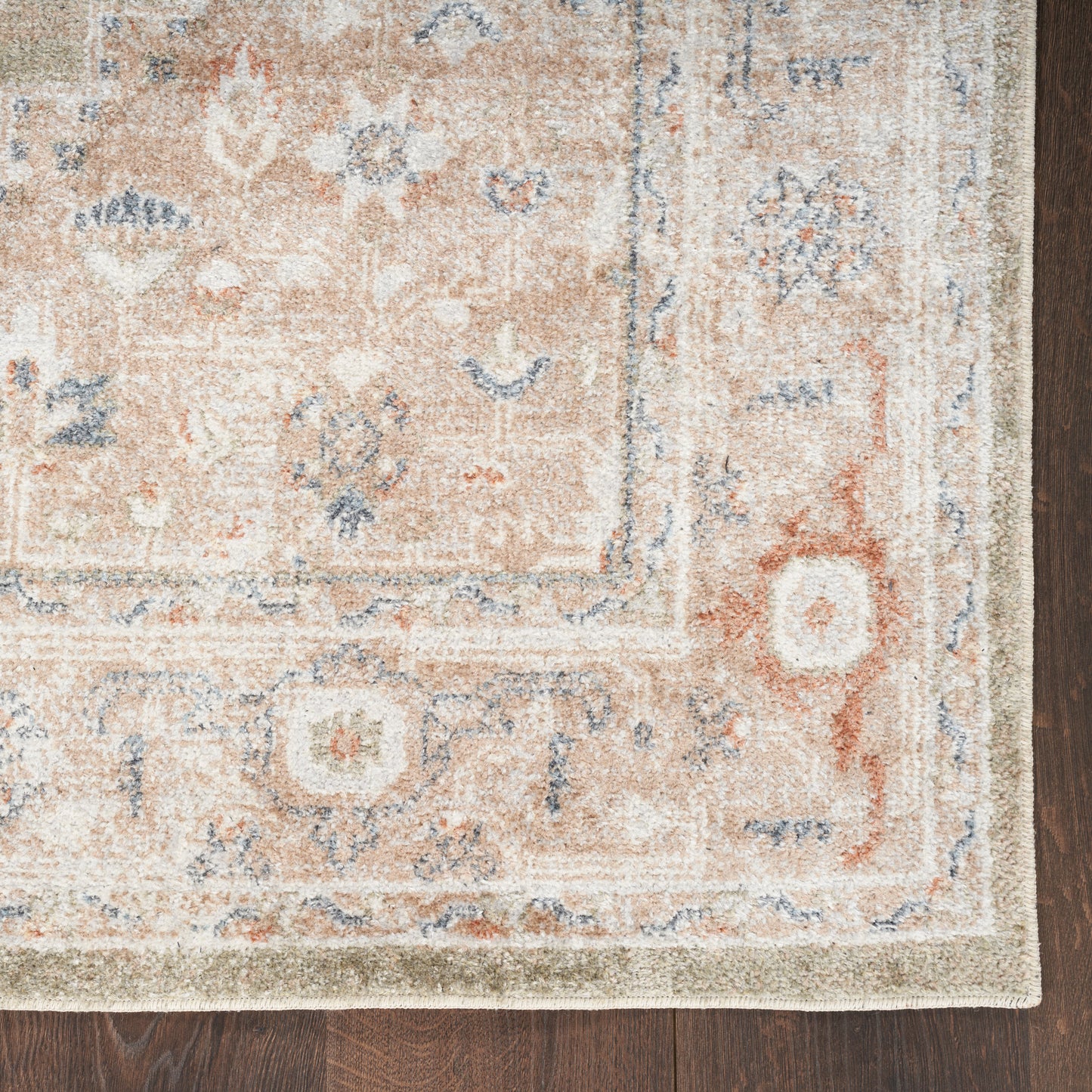 Beige peach oriental rug with blue floral motifs and an ornate border on dark wood floor, 7' x 9'.